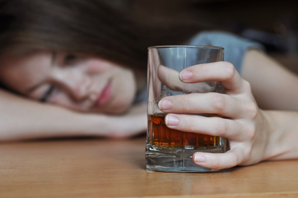 Young drunk woman holding a glass of whiskey