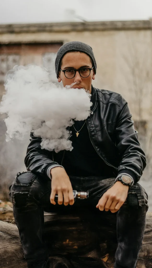 young man sitting on steps vaping