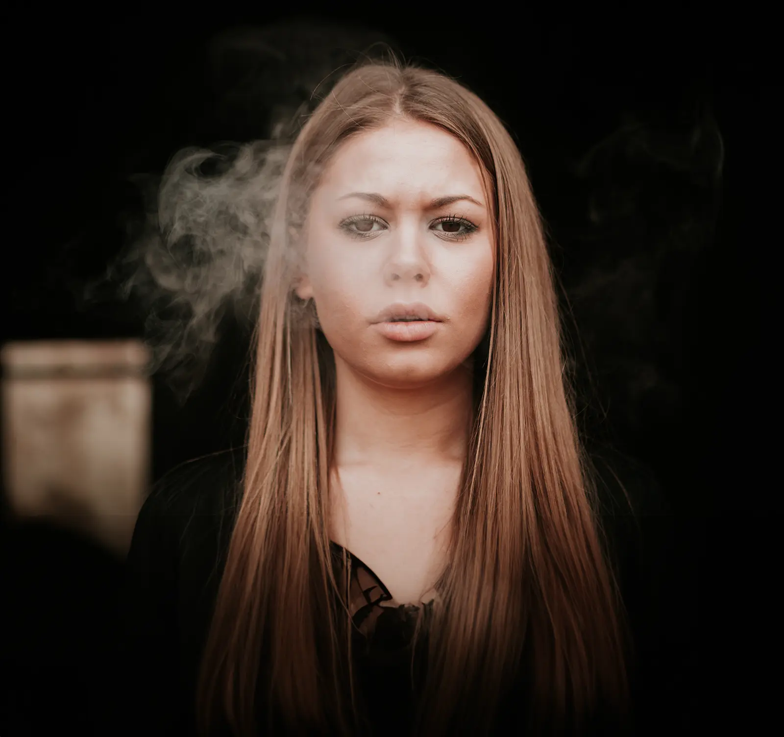 young girl blowing out puff of smoke