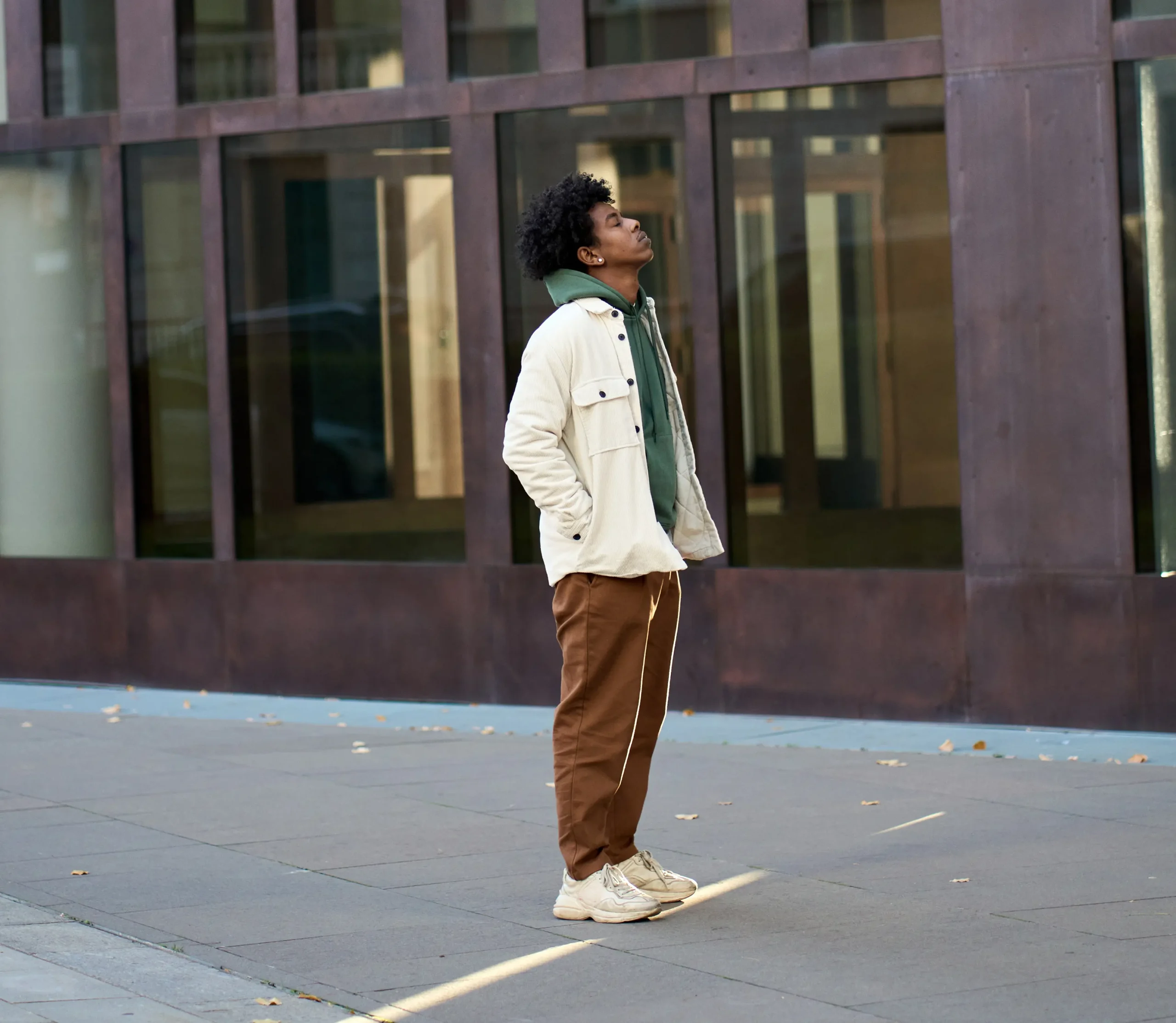 young boy standing in front of a building looking up