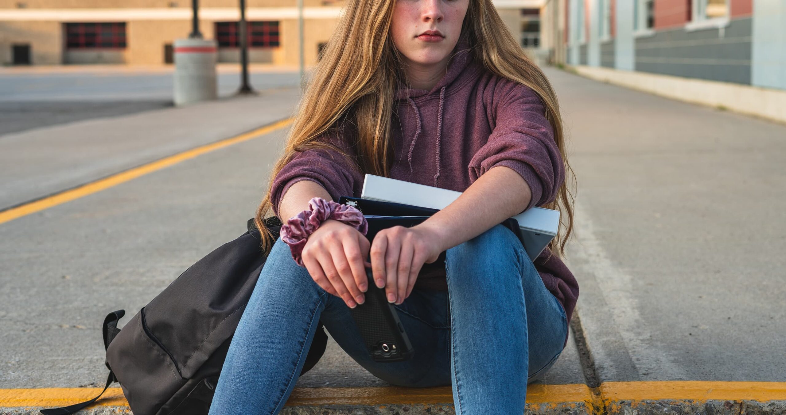 young girl sitting with backpack and notebooks